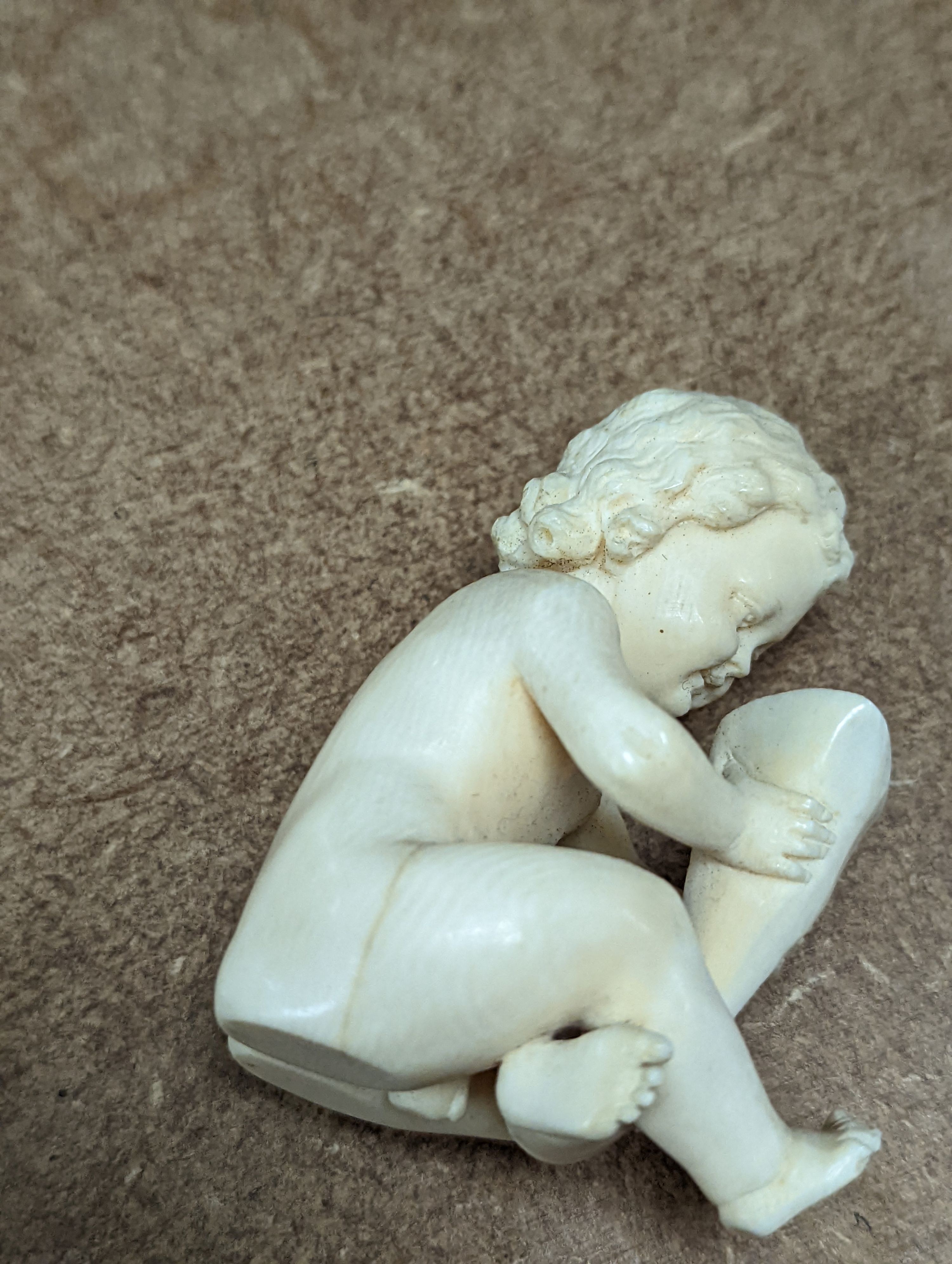 A 19th century Continental carved ivory figure of a child holding a cornucopia - 7cm tall